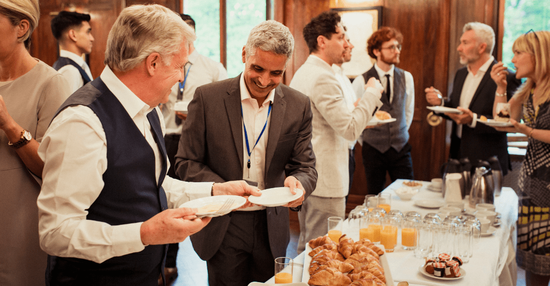 Conference attendees enjoying breakfast service in hotel meeting space.